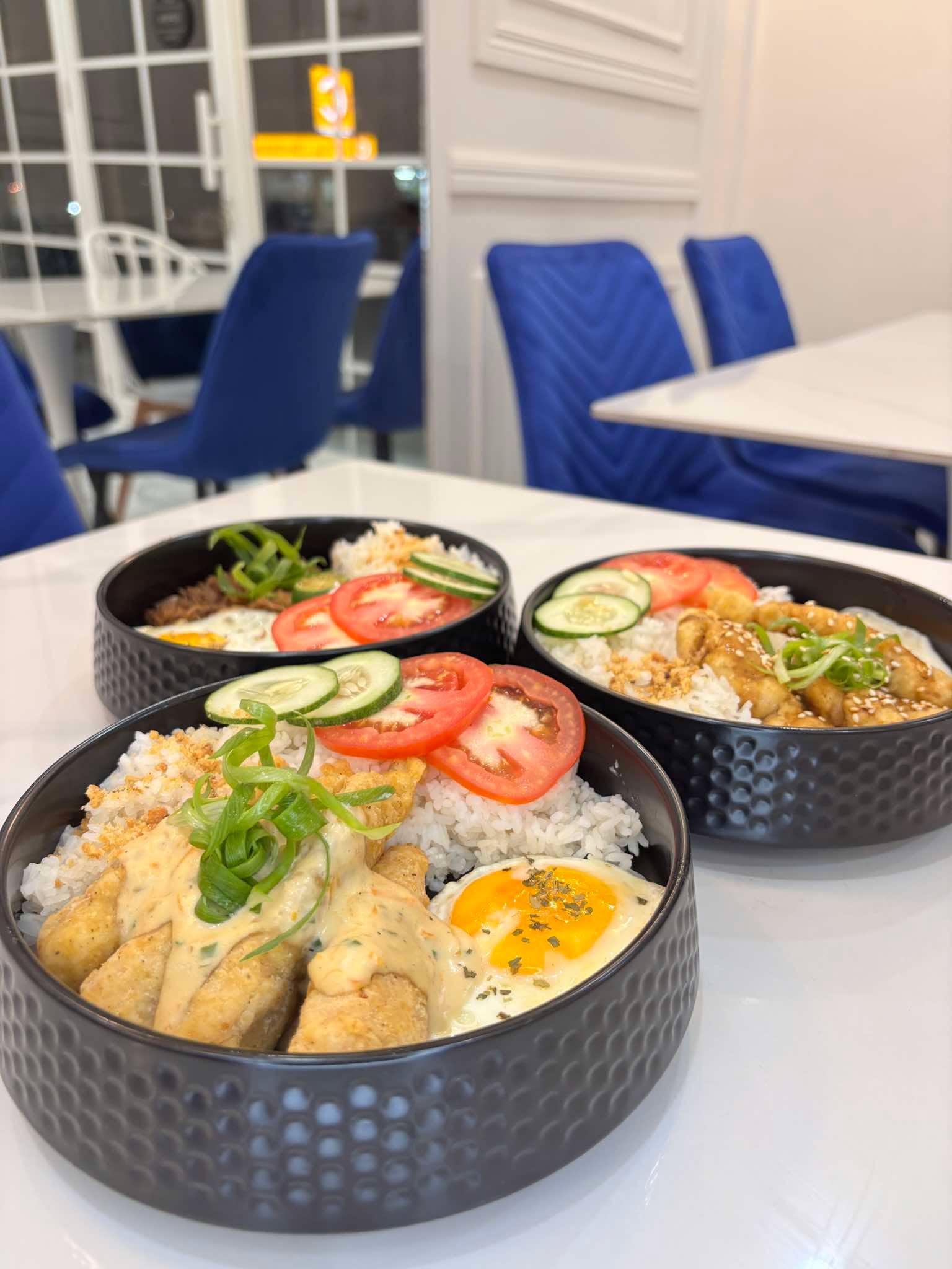 Rice bowls on a marble table with the dining room seating behind